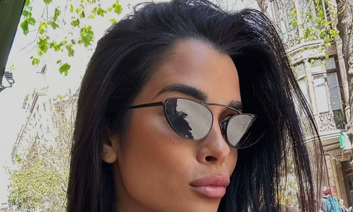 Lunettes de soleil à monture noire, verres fumés; portées par une femme