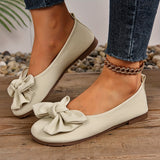 Ballerines à bout arrondi beige à nœud, portées avec jeans