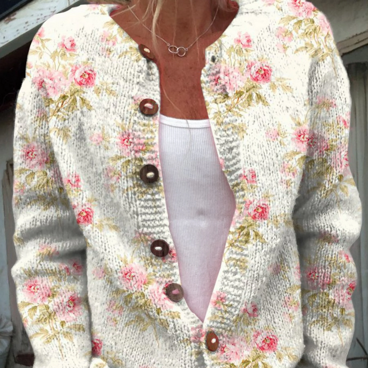 Cardigan en maille claire à boutons, décolleté en V, fleurs roses et feuilles vertes.