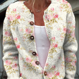 Cardigan en maille claire à boutons, décolleté en V, fleurs roses et feuilles vertes.