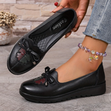 Mocassins noirs à nœud, cuir texturé, détail floral et lacet sur le dessus.