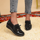 Mocassins noirs à bout brillant verni, nœud décoratif et petit détail doré.