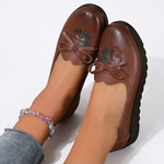 Mocassins bordeaux en cuir à nœud, semelle crantée, détail floral sur le dessus.