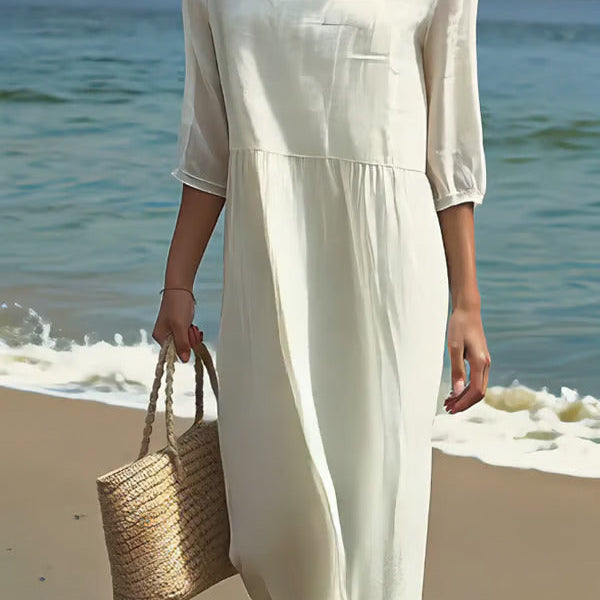 Robe blanche ample à encolure carrée, manches trois-quarts, taille froncée.