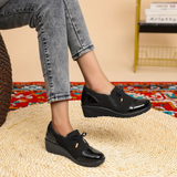Mocassins noirs vernis à semelle épaisse, nœud et petit pendentif doré sur le dessus.