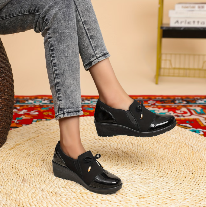 Mocassins noirs vernis à semelle épaisse, nœud et petit pendentif doré sur le dessus.
