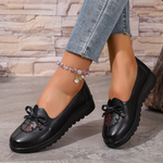 Mocassins noirs à nœud, semelle crantée, détail floral en relief sur le dessus.