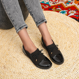 Mocassins noirs à bout lustré, nœuds sur l’empeigne et détails dorés sur le côté.