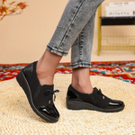 Mocassins noirs vernis avec empiècement texturé, nœud sur le dessus et semelle épaisse.