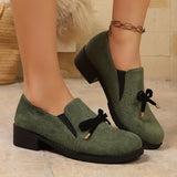 Mocassins en daim vert avec nœud noir, talon bloc et semelle noire.