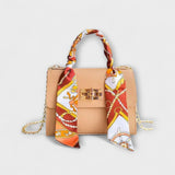 Sac à main beige avec foulard imprimé rouge et blanc, rabat et fermoir rectangulaire.