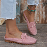 Sabots mocassin en daim rose poudré, nœud décoratif et semelle épaisse à picots.