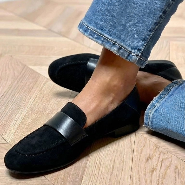 Chaussures mocassin noir à bride, portées avec jean bleu sur sol en bois