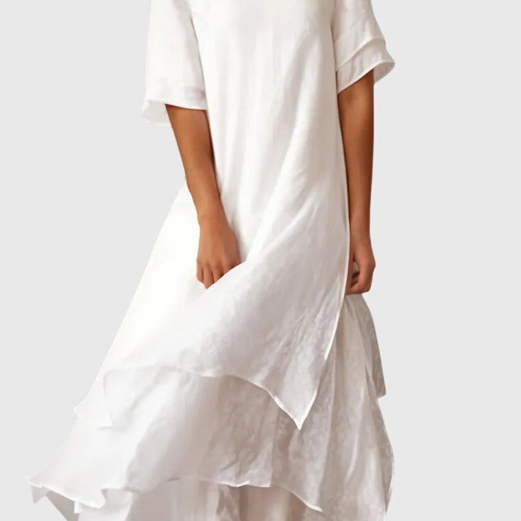 Robe mi-longue blanche, manches courtes, encolure ronde, jupe évasée avec volant.