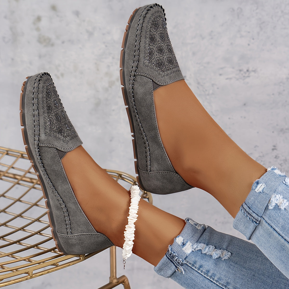 Mocassins gris foncé ajourés, motif floral sur l’empeigne et semelle crantée.