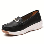 Mocassins noirs à bout rond, semelle blanche épaisse, bride décorative en métal doré.