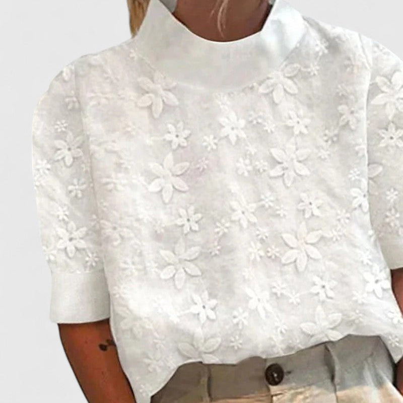 Blouse blanche à col montant, broderie de fleurs appliquées, manches courtes.