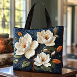 Sac tote matelassé bleu nuit avec magnolias blancs en appliqué et anses noires.
