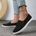 Chaussures souples à enfiler noires, chaînette dorée à la cheville, semelle blanche.