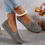 Mocassins gris ajourés avec motif floral sur l’empeigne et coutures décoratives.