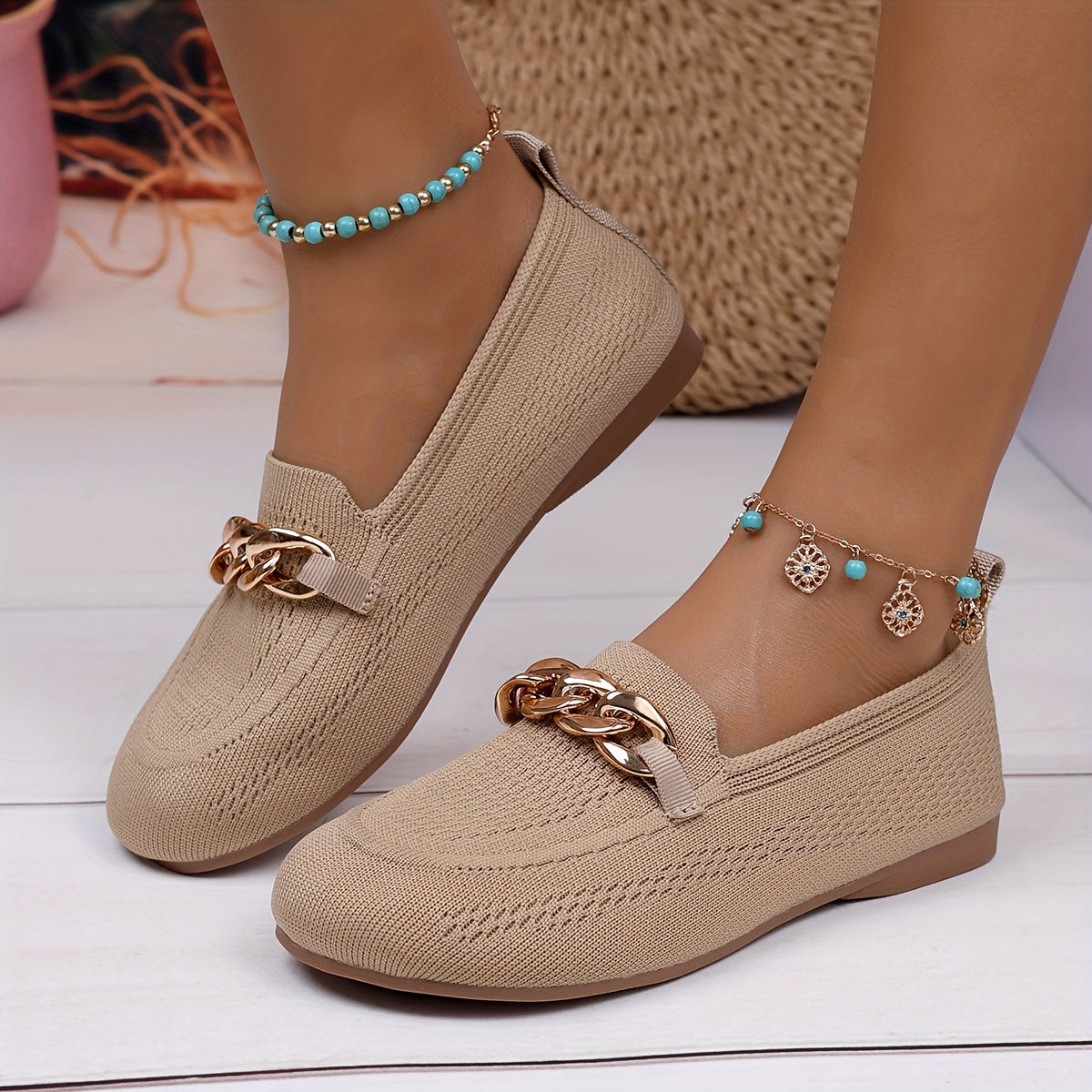 Chaussures plates beiges à bordure souple et chaîne dorée décorative sur le dessus.