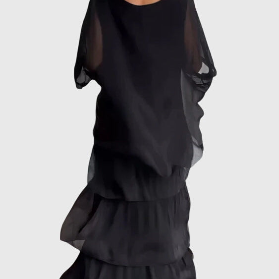 Robe longue fluide noire, en mousseline, manches longues bouffantes et volants superposés.