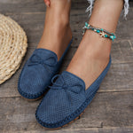 Sabots mocassin en daim bleu marine, dessus perforé et nœud décoratif au bout.
