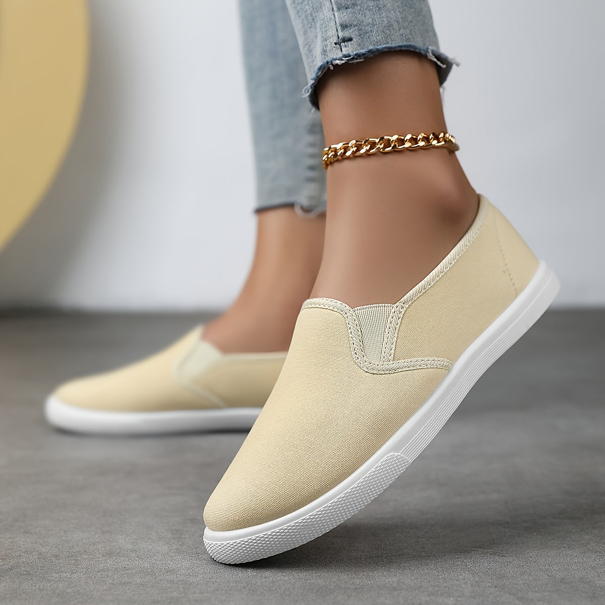 Chaussures souples à enfiler beige clair, chaînette dorée à la cheville, semelle blanche.