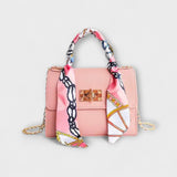 Sac à main rose avec foulard imprimé, rabat, fermoir rectangulaire, chaîne dorée.