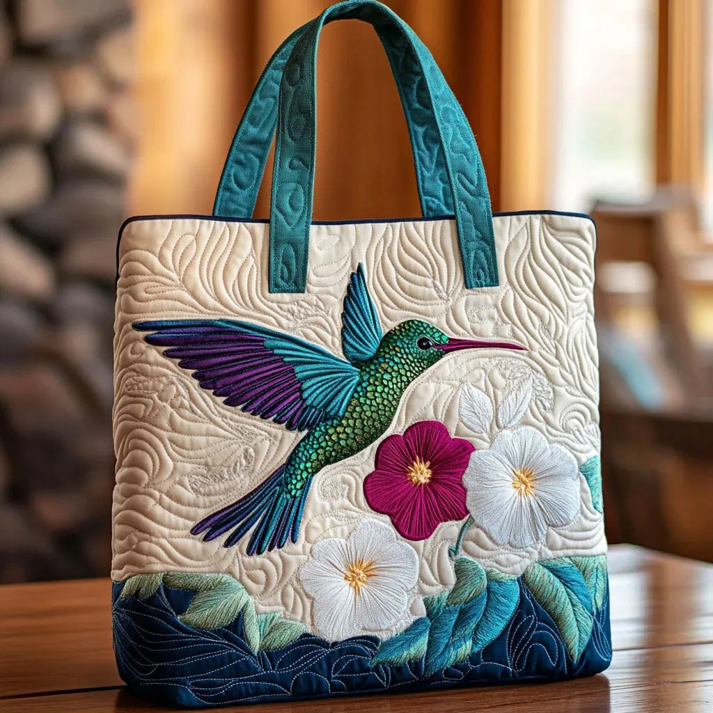 Sac matelassé blanc avec oiseau multicolore et fleurs brodées, anses bleues.