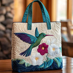 Sac matelassé blanc avec oiseau multicolore et fleurs brodées, anses bleues.