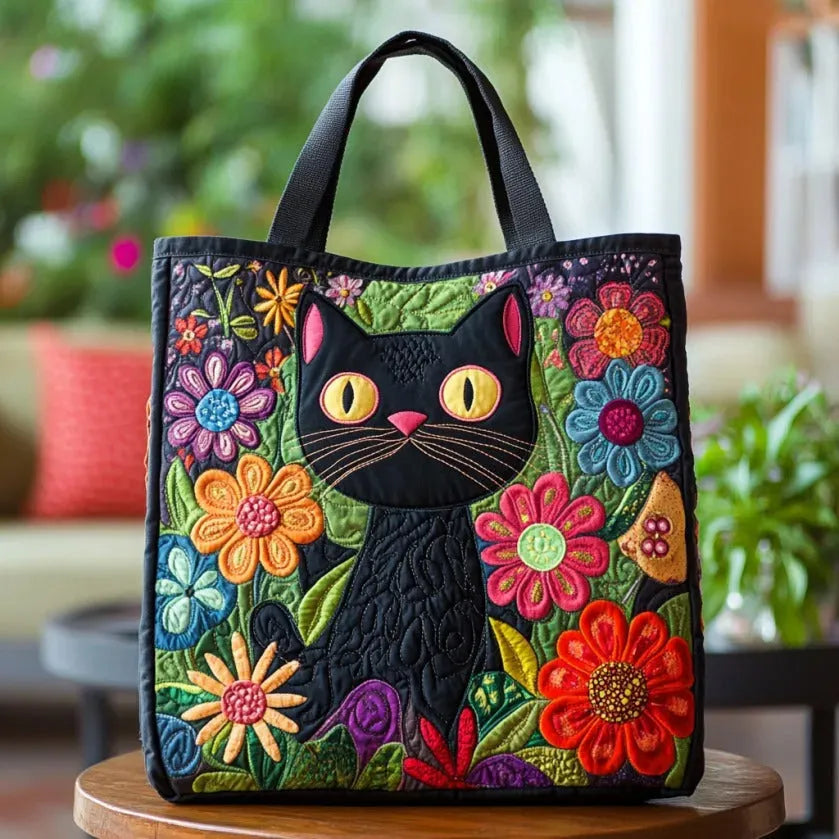 Sac cabas matelassé noir avec tête de chat brodée et fleurs colorées, anses courtes.