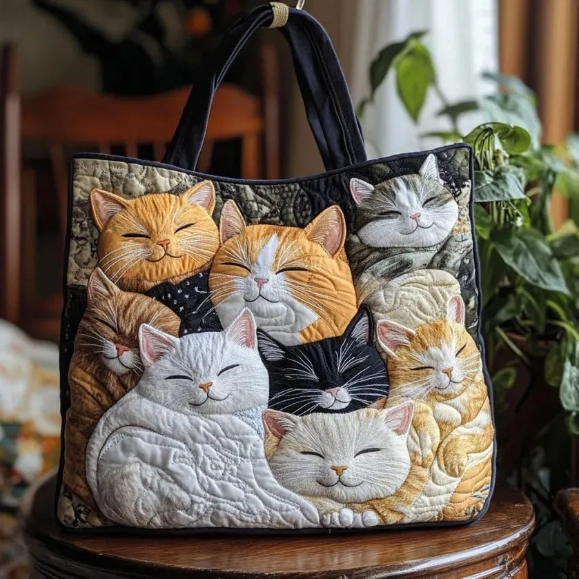 Grand sac matelassé sombre avec anses et motif de chats endormis en appliqués.