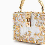 Sac rectangulaire blanc à motifs dorés, fermoir carré central et poignées dorées