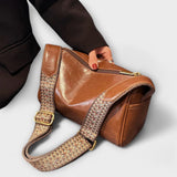 Sac bandoulière vintage en cuir brun caramel, bandoulière tressée et boucle dorée.