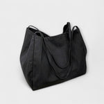 Sac cabas en toile noire, grandes anses et surpiqûres, forme évasée.