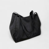 Sac cabas en toile noire, grandes anses et surpiqûres, forme évasée.