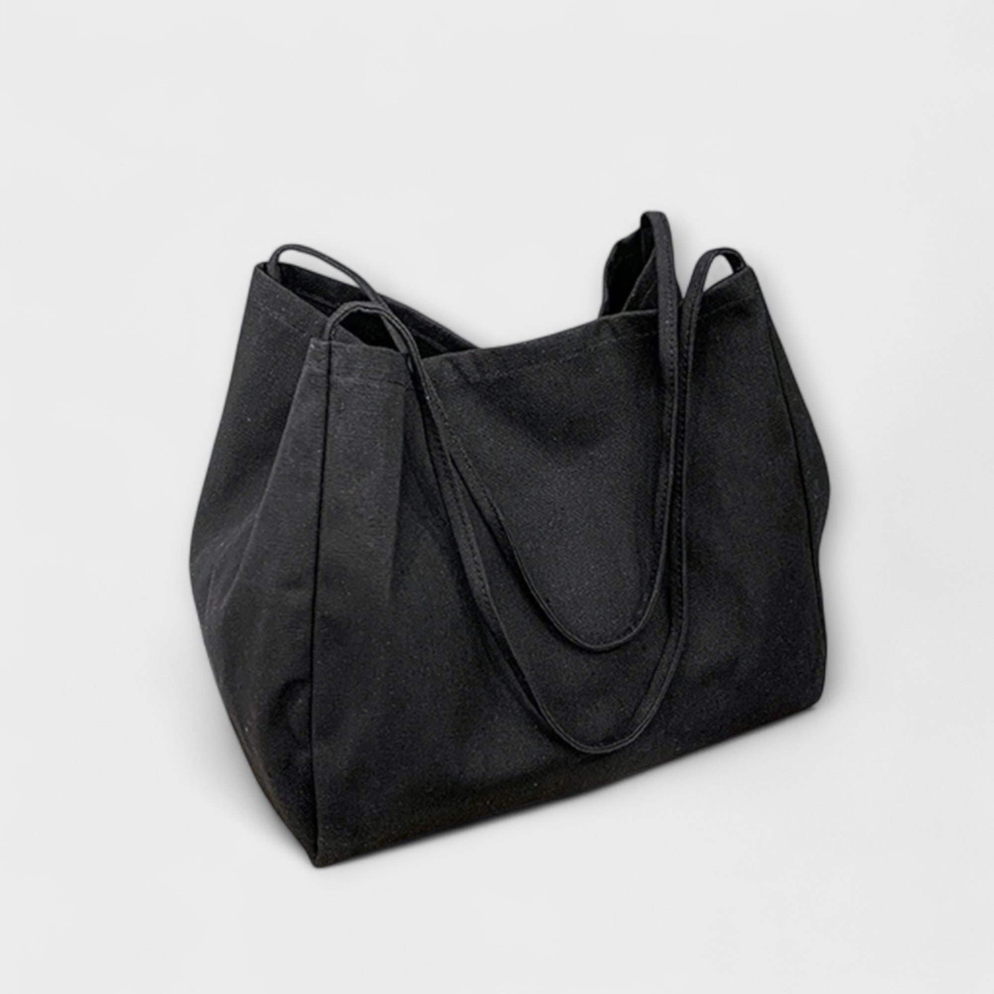 Sac cabas en toile noire, grandes anses et surpiqûres, forme évasée.