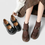 Chaussures bébé en cuir noir et marron, brides à boucle et semelle plateforme épaisse.
