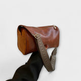 Sac bandoulière vintage en cuir brun, bandoulière tressée à motif et boucle.