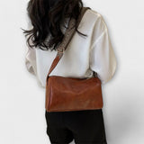 Sac bandoulière vintage en cuir marron, bandoulière tressée et fermeture à boucle.