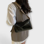 Sac bandoulière vintage en cuir noir lisse, bandoulière tressée à boucle réglable.