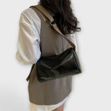 Sac bandoulière vintage en cuir noir lisse, bandoulière tressée à boucle réglable.
