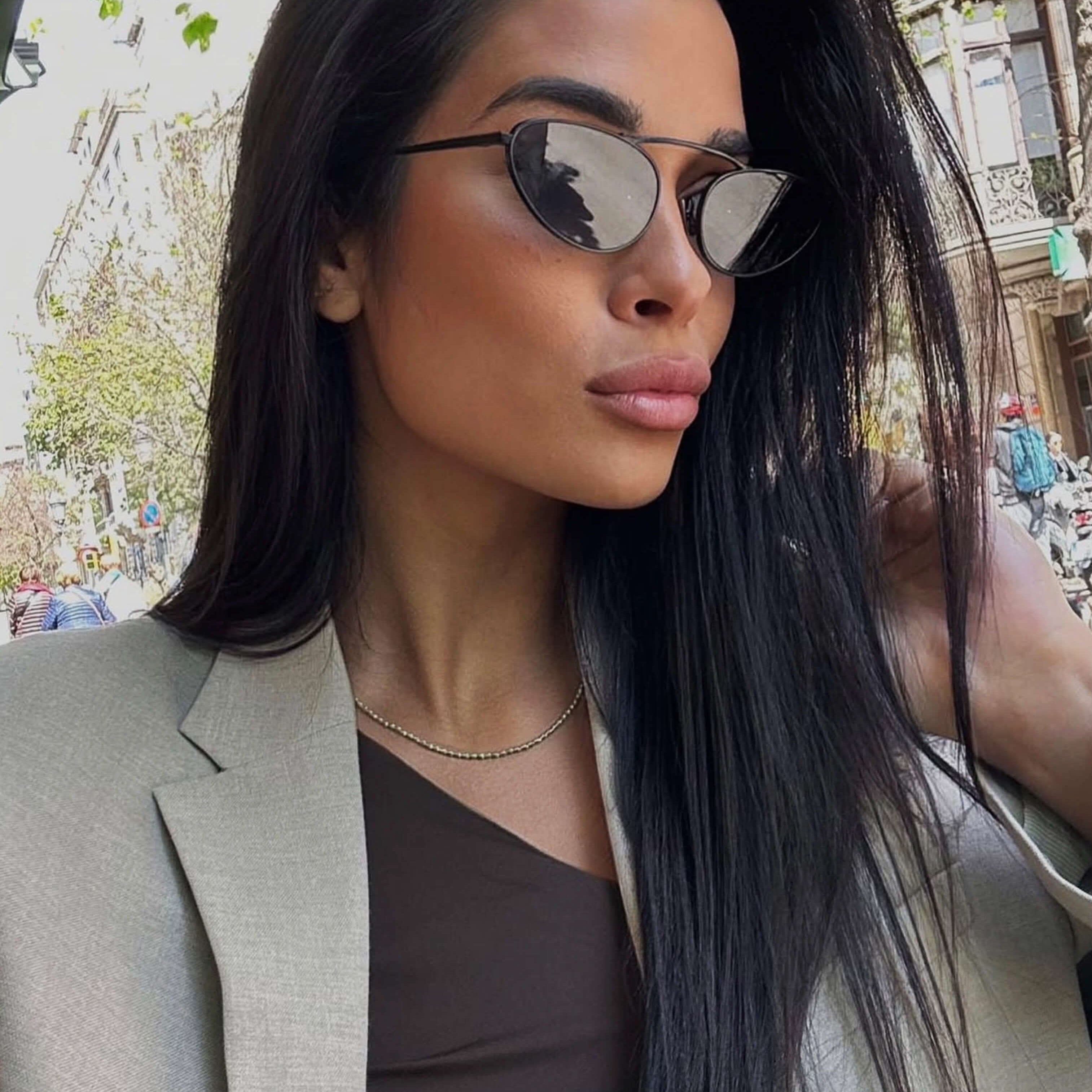 Lunettes de soleil à monture noire, verres fumés; portées par une femme