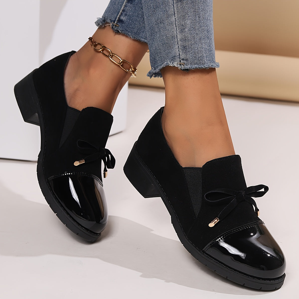 Mocassins Nadège noirs à talon bloc, bouts vernis et nœud sur l’empeigne.