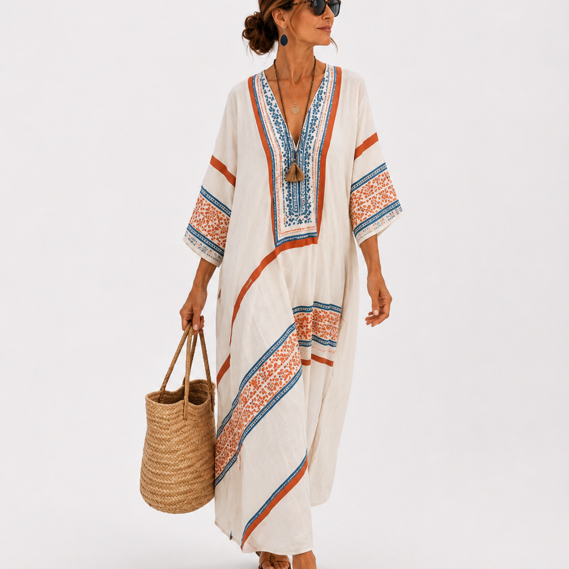 Caftan long blanc à col en V, liserés et motifs bleus et orange, manches larges.