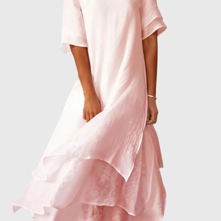 Robe mi-longue rose pâle, manches courtes, encolure ronde, jupe évasée avec volant.