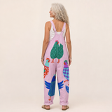 Salopette rose vue de dos, bretelles lilas croisées et motif oiseaux sur l’ensemble.