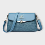 Sac à bandoulière bleu en cuir tressé, rabat avec fermoir fleur, logo BALDASHU