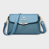 Sac à bandoulière bleu en cuir tressé, rabat avec fermoir fleur, logo BALDASHU